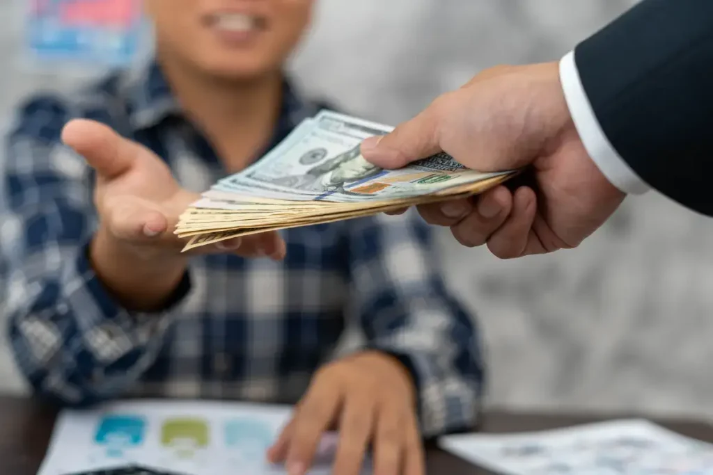Imagem de um homem emprestando dólares para outro, representando credito para compra de terreno e construção.