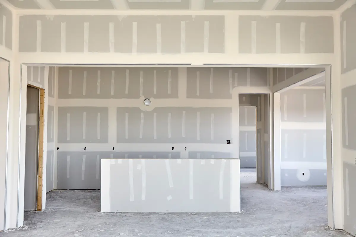 Drywall é uma opção segura para residências? Comparação visual de um ambiente antes e depois da instalação do drywall, mostrando os benefícios em resistência e isolamento. Foto: Reprodução / Canva Pro.