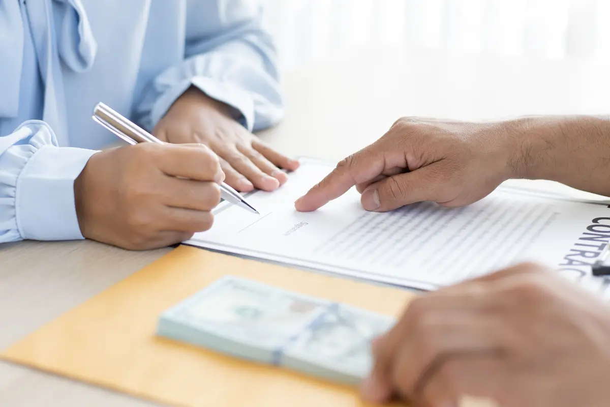 Alienação fiduciária no financiamento de terrenos! Imagem representando um contrato de financiamento sendo assinado. Foto: Reprodução / Canva Pro.