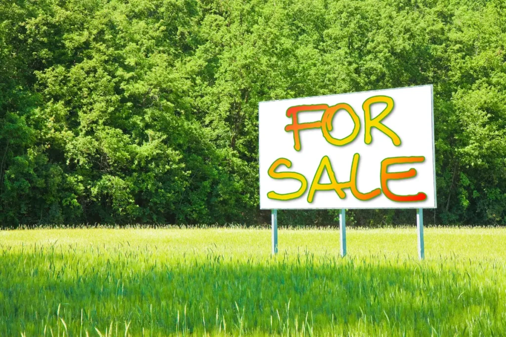 Descubra como vender terreno comercial de forma rápida. Placa de “Vende-se” em destaque com fundo urbano desfocado. Foto: Reprodução / Canva Pro.