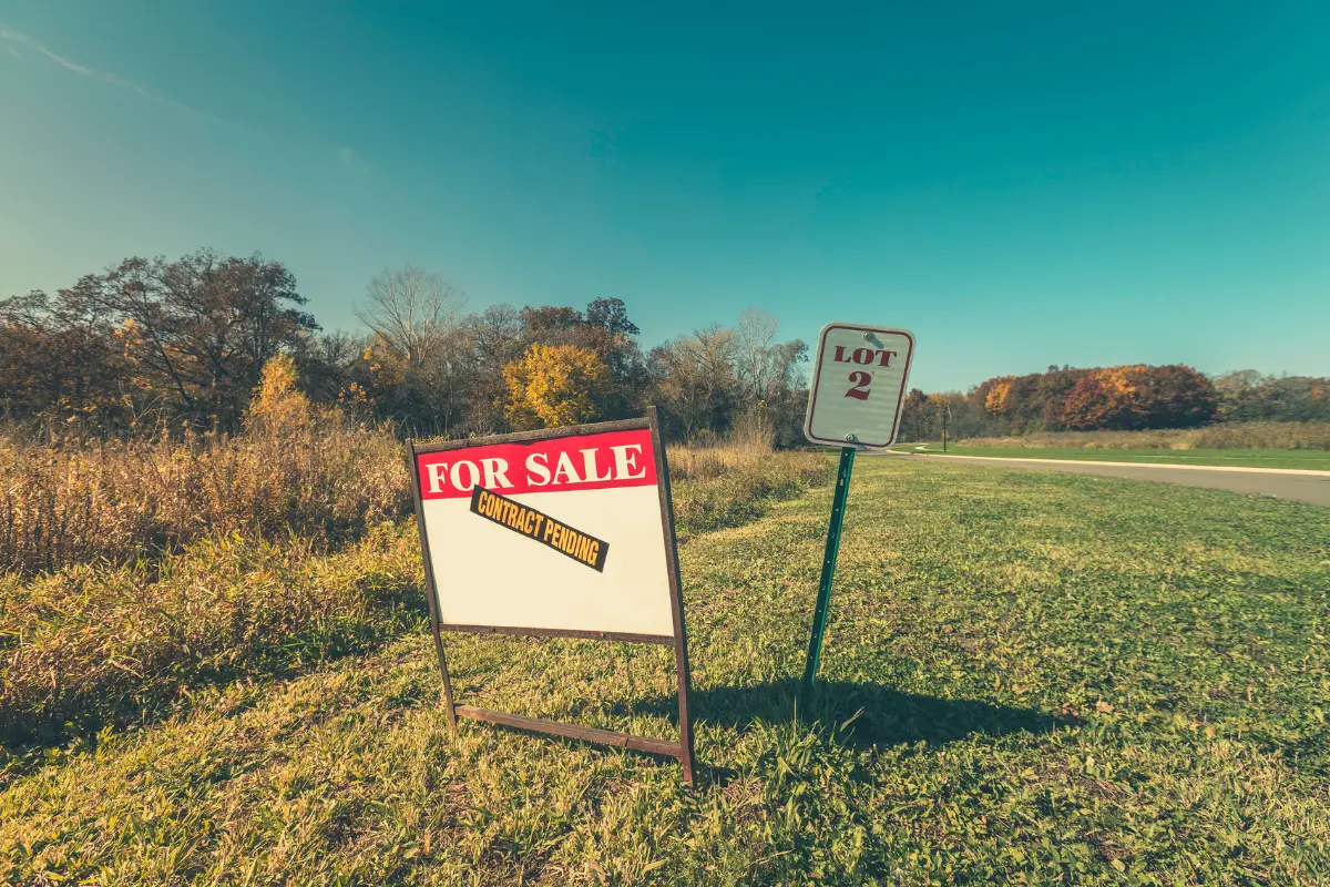 Lote barato: Placa de lote à venda com foco parcial instiga dúvidas sobre onde economizar na aquisição. Foto: Reprodução / Canva Pro.