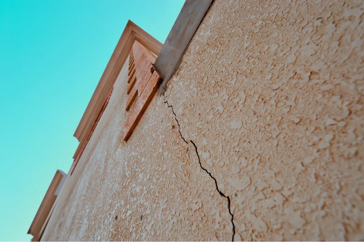 Como identificar risco geológico de um terreno: Cidadão observa rachaduras na parede e teme pelo futuro da casa. Foto: Reprodução / Canva Pro.